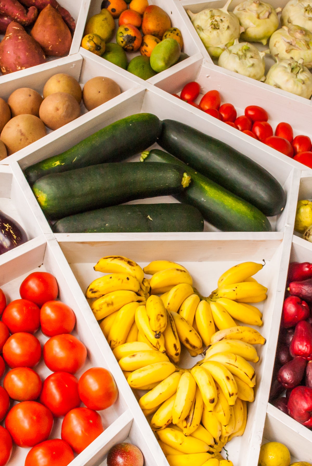 A wooden crate of just-picked zucchini, yellow squash and tomatoes