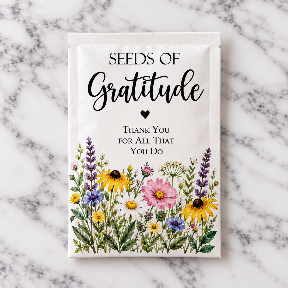 The Seeds of Gratitude wildflower seed packet, printed with daisies, cosmos, black-eyed Susans and lavender and reading Thank You for All That You Do, on white marble
